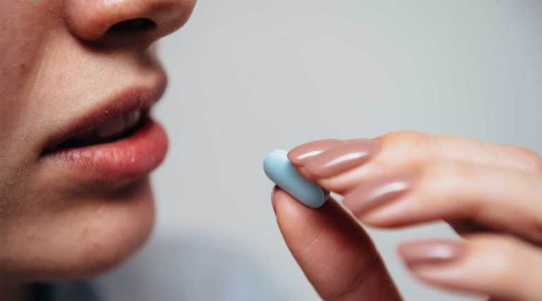 Young woman taking a blue pill prescription opioid