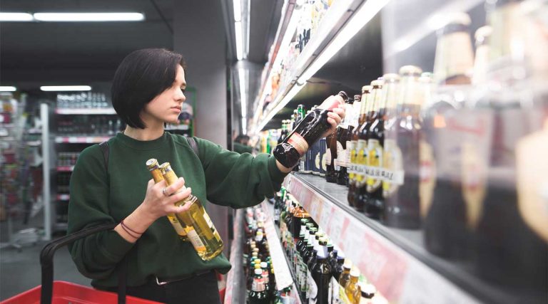 young woman buying alcohol in a super market