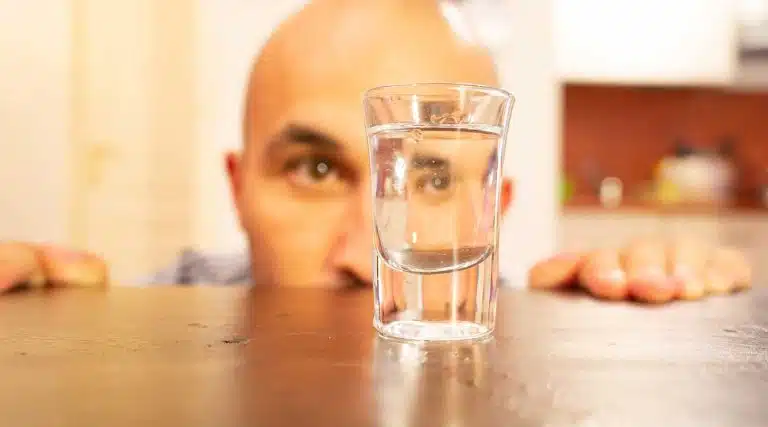 man looking at an empty shot glass
