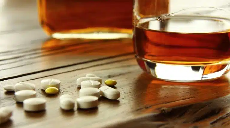 various colorful pills and alcohol whiskey on a table
