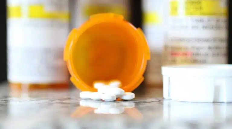 orange pill bottle spilled out on a table white round pills