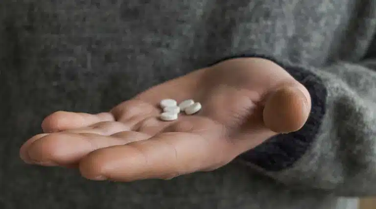 young man attempting to take a handful of Oxycodone opioid pills