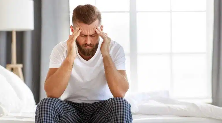 man holding his head experiencing Halcion Withdrawal symptoms