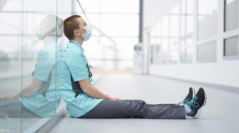 young woman nurse sitting on the floor of a hospital Healthcare Worker Burnout