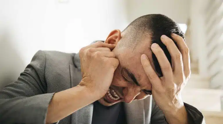 young man in pain holding his head and yelling experiencing cocaine psychosis