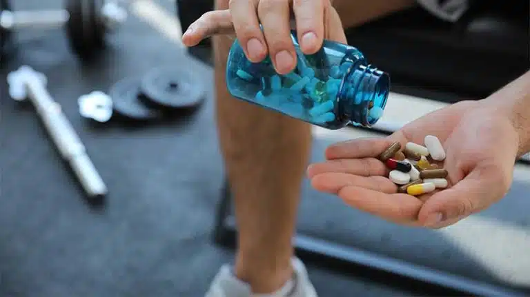 man at the gym holding a pile of pills - High School Athletes & Future Prescription Stimulant Abuse