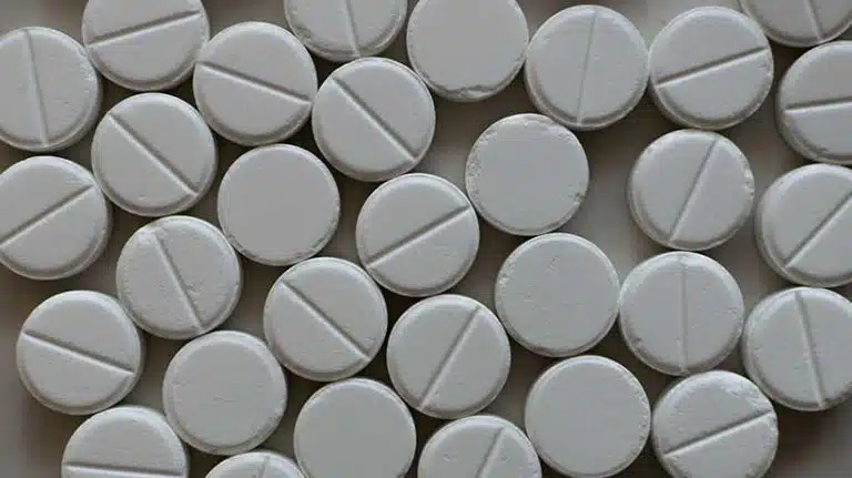 round white pills in a pile on a table - Is Oxycodone A Narcotic?