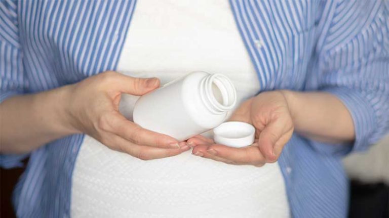 pregnant woman reading a prescription pill bottle - Oxycodone And Breastfeeding | Is It Safe?