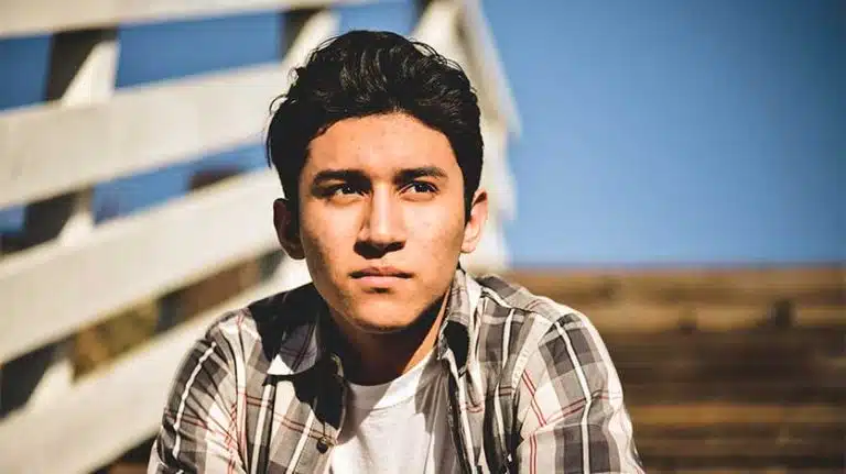 young man sitting on steps looking off into the distance - Hispanic/Latino Mental Illness And Addiction Prevalence In The U.S.