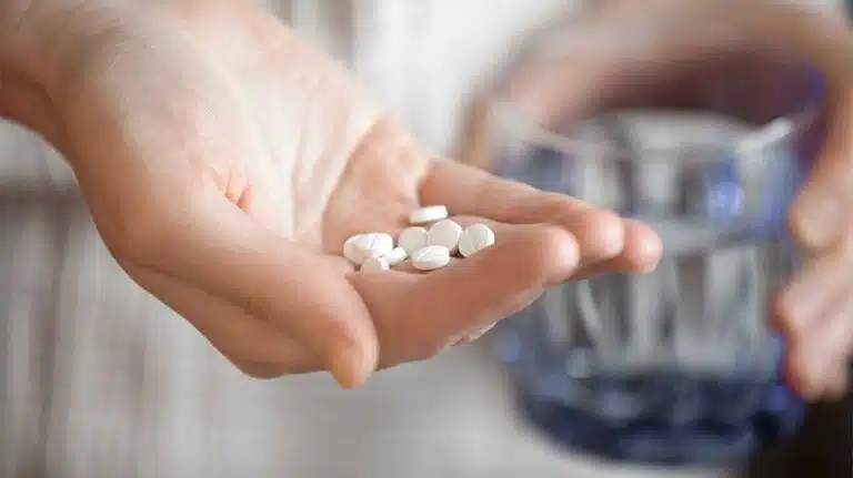 woman holding handful of white pills - Lexapro Dosage Guide For MDD, GAD, OCD, & More