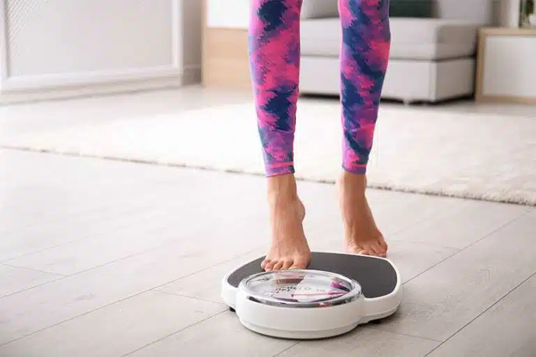 Woman Stepping On Scale-Ozempic For Weight Loss | Trends, Risks, & Abuse